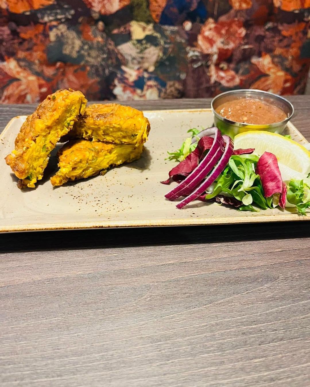 Golden pakora served with salad, red onion, lemon and chutney