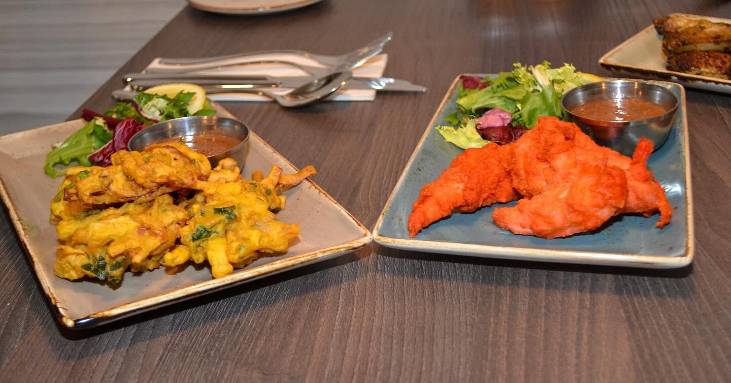 Vegetable pakora and chicken pakora starters with salad and dipping sauce